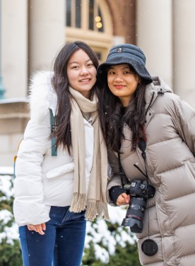 two women in front of foellinger auditorium in light snow