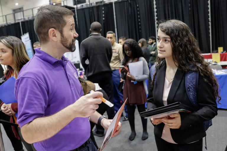 female student talks with male career fair participant at fair