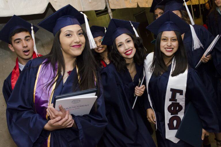 Group of Hispanic graduates in caps and gowns smiling
