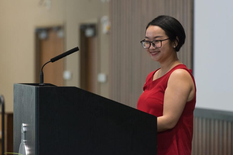 Asian female with glasses smiling at podium