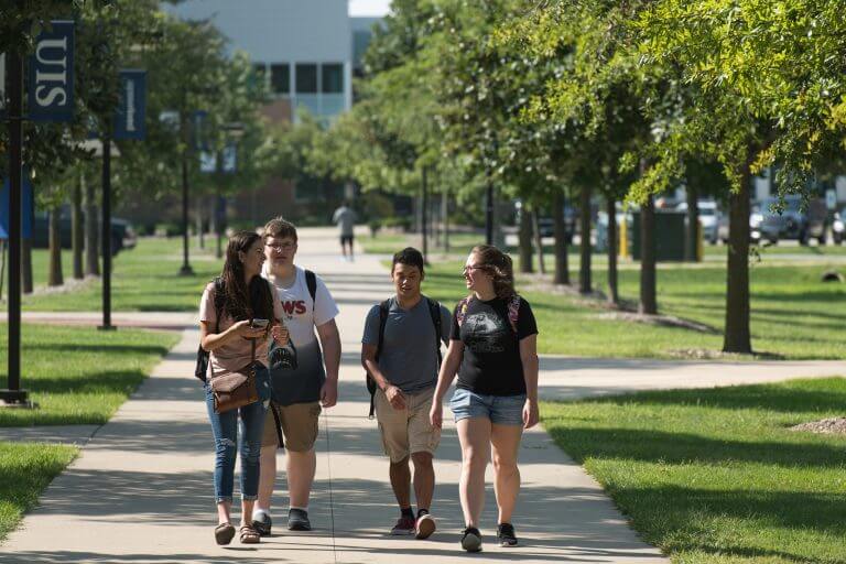 group of students walking on the UIS quad down tree-lined walk