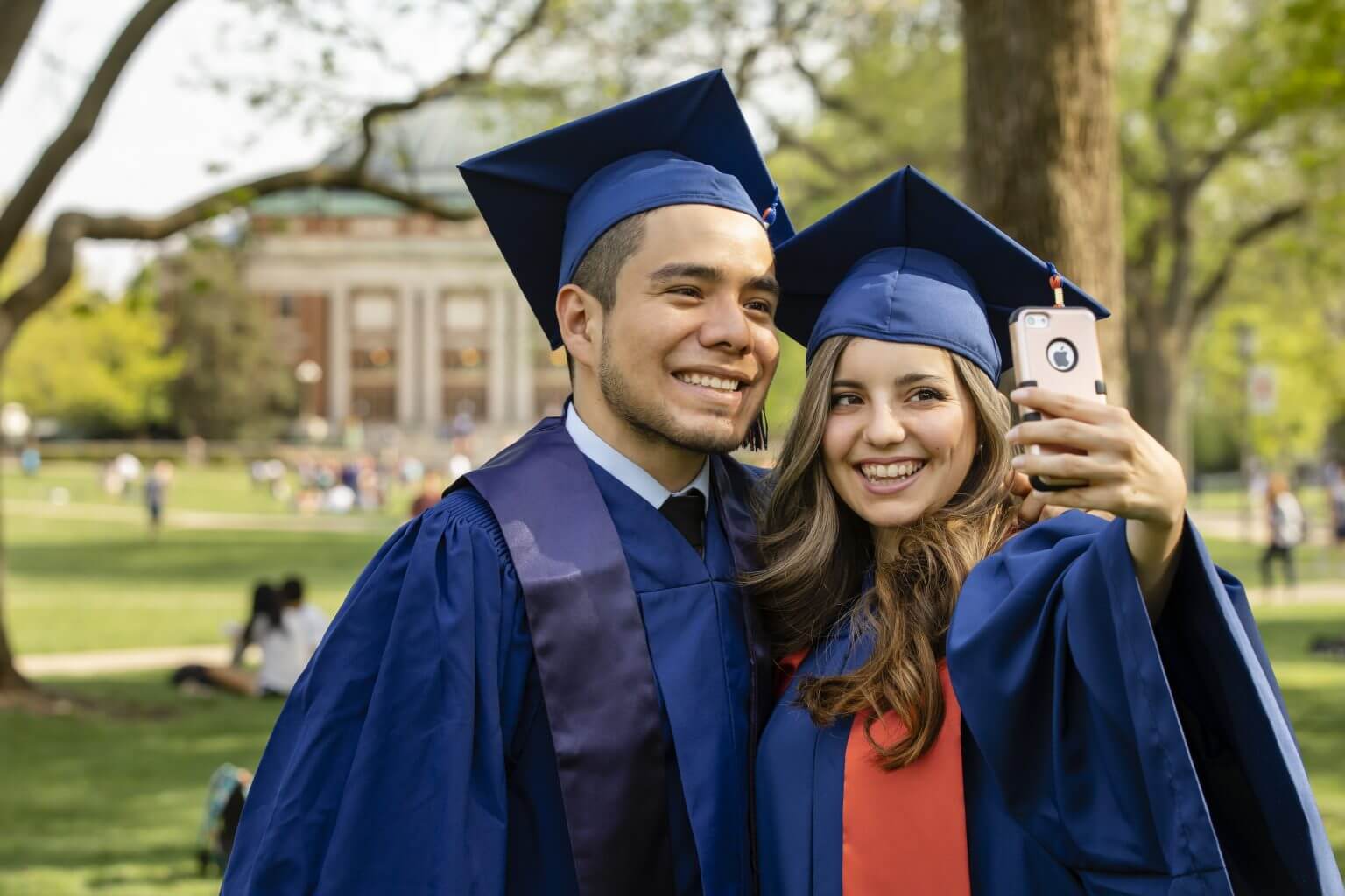 College of ACES graduating seniors in caps and gowns taking selfie on the quad