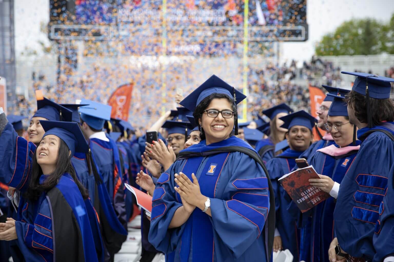 A female doctoral student smiles during the confetti toss at the end of the University of Illinois Commencement at Memorial Stadium, May 11, 2019.