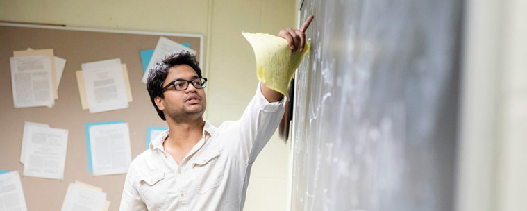 man pointing to chalkboard in classroom