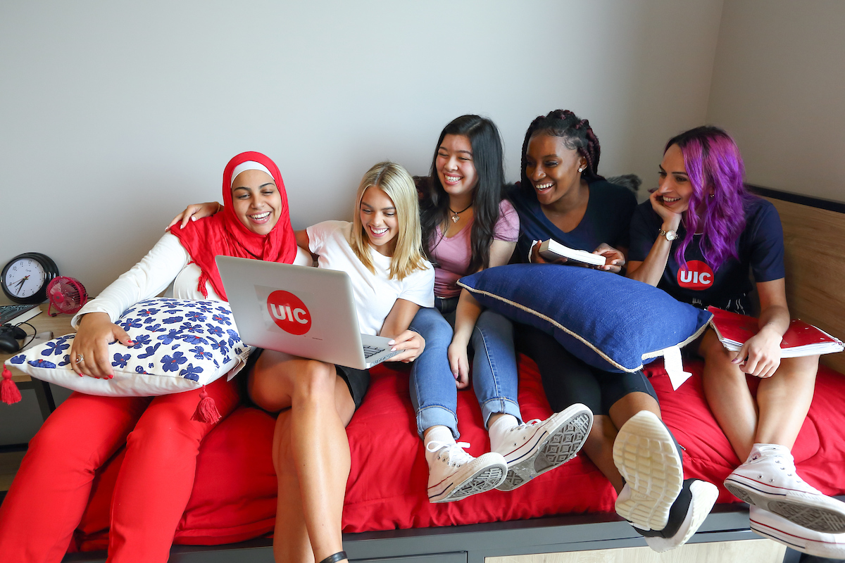 diverse group of UIC students laughing on bed