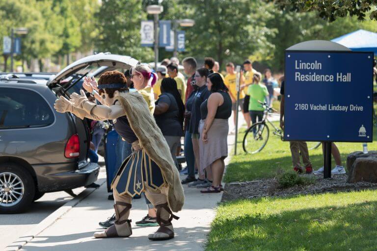 29267768207_59a1c75b3b_o-768x512.jpg families unload belongings from cars on move-in day outside of Lincoln Residence Hall, while mascot Orion cheers on