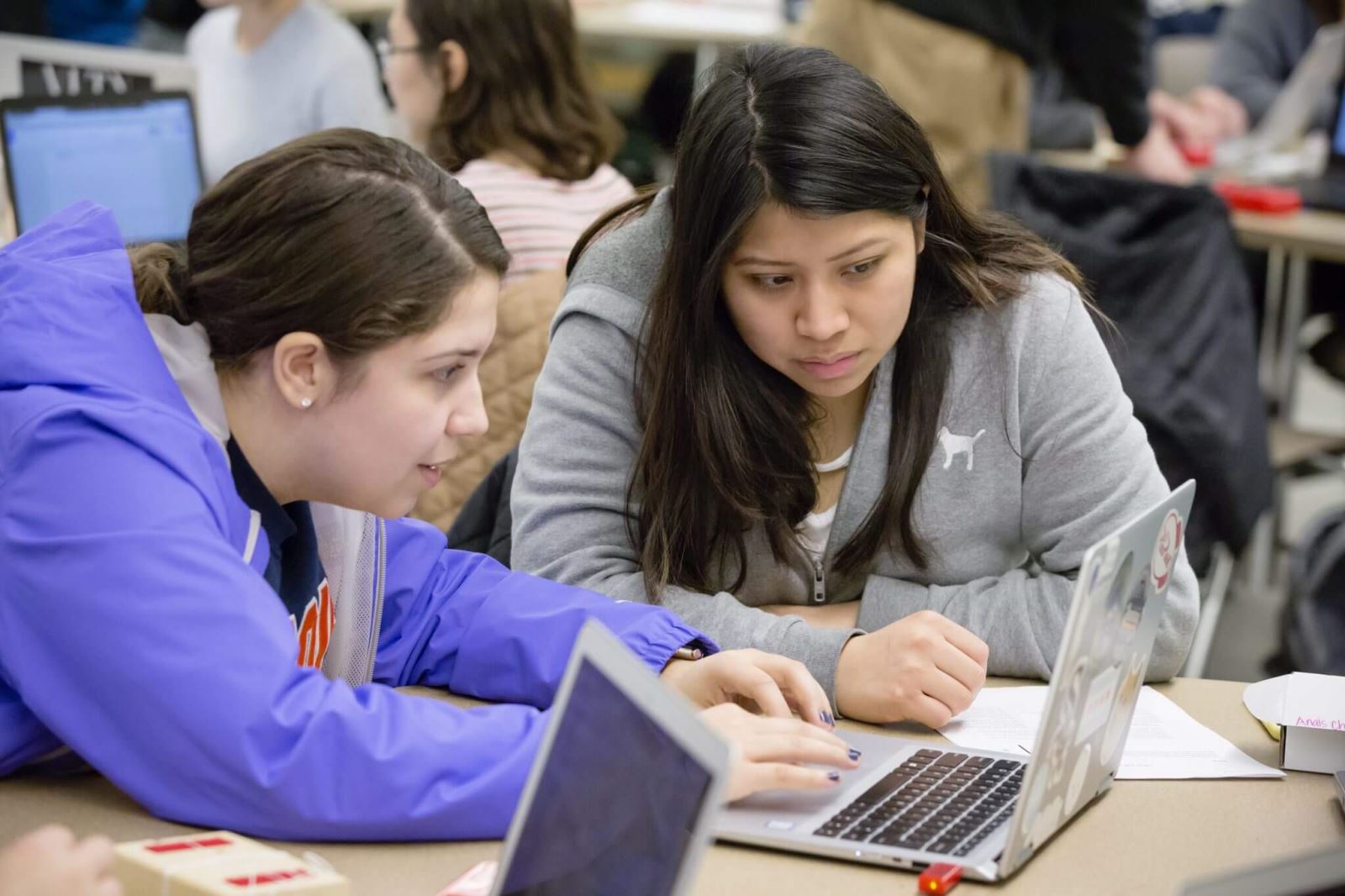 two women hunched over a laptop looking at screen