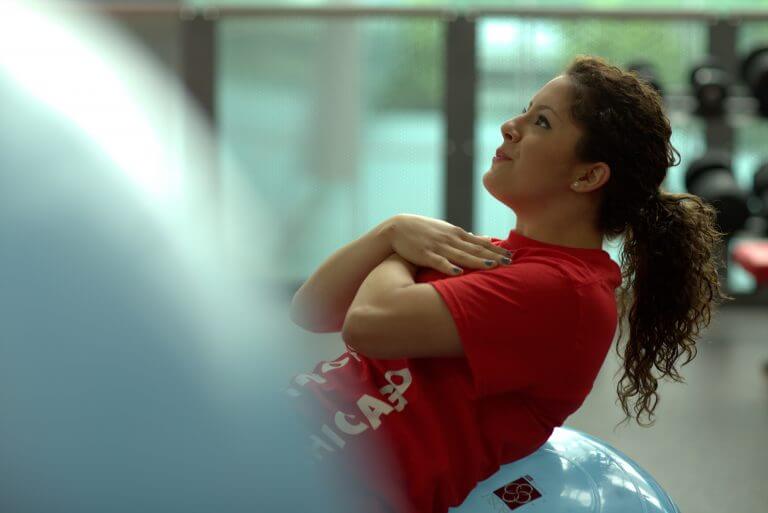 UIC_2015-3347-768x513.jpg female in pony tail and T'shirt doing situps against a rubber ball