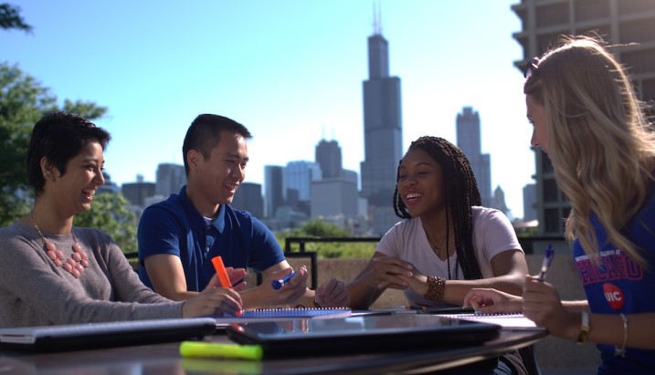 students sitting at a table with Chicago skyline in background